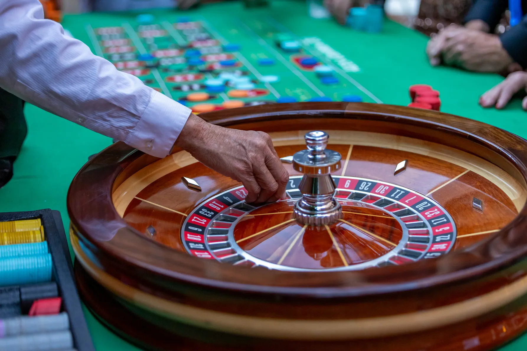 Croupier som spinner rulett ved et grønt casinobord