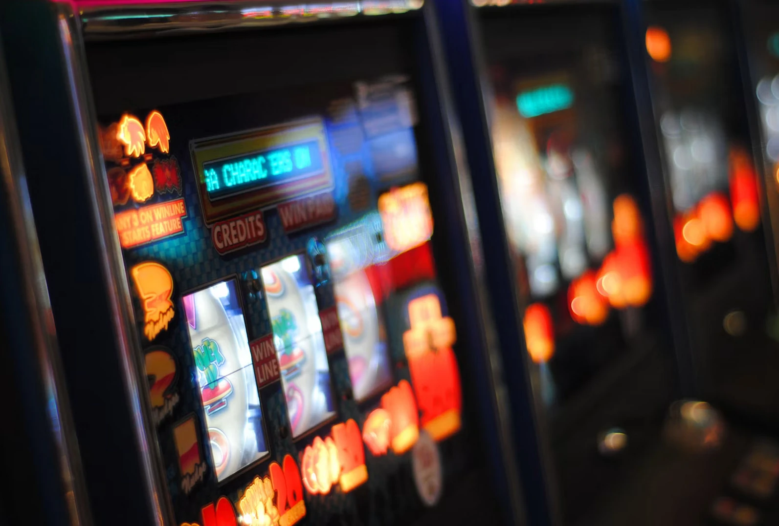 Rekke med opplyste spilleautomater i et casino